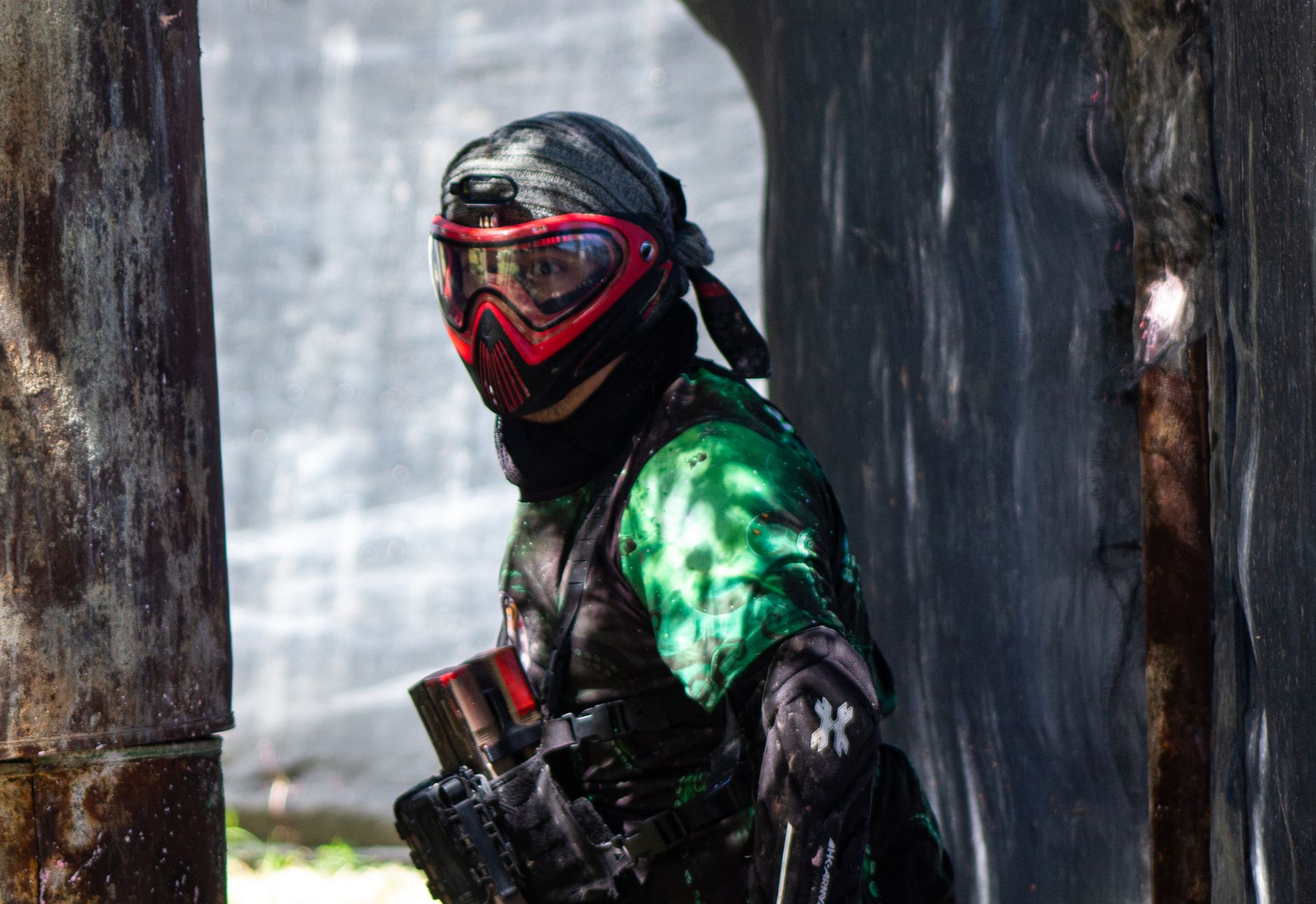 Hráč paintballu v maske za bunkrom na lesnom ihrisku